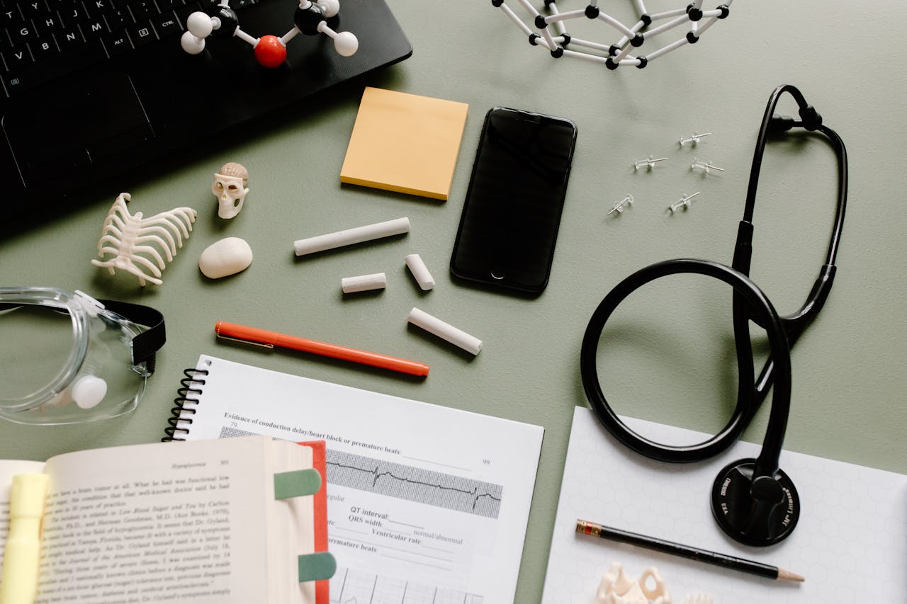Flat lay of medical study desk with a stethoscope, books, and molecular models.